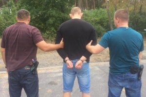 policjanci prowadzą zatrzymanego zakutego w kajdanki