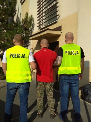 dwaj policjanci prowadzą zatrzymanego mężczyznę