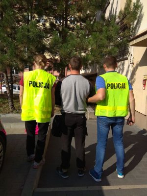 dwaj policjanci prowadzą zatrzymanego mężczyznę