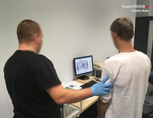 Technik kryminalistyki pobiera odciski palców od podejrzanego