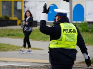 policjant tyłem z podniesioną ręką