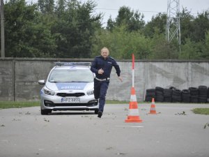 biegnący policjant, radiowóz w tle