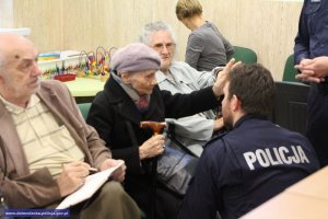 Policjanci rozmawiają o zagrożeniach z seniorką