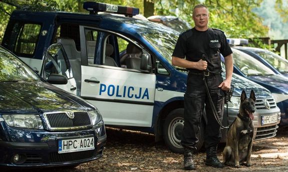 Na zdjęciu znajduje się policjant wraz z psem tropiącym