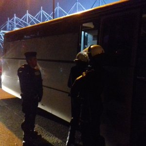 Policjant eskortuje zatrzymanego do więźniarki