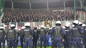 Policjanci stoją na płycie stadionu przed sektorem gości