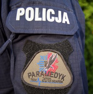 Naszywka na mundurze z napisem Paramedyk. Powyżej napis Policja