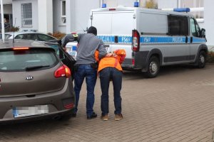 policjant prowadzi zatrzymanego mężczyznę