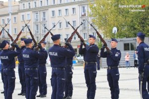 policjanci w dwóch szeregach naprzeciwko siebie, z karabinami na ramieniu wzniesionymi w górę