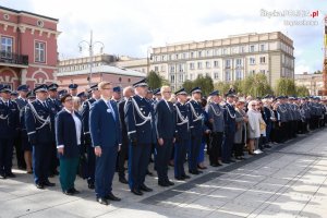 Policjanci i goście zaproszeni stojący w szyku na tle Ratusza Miejskiego