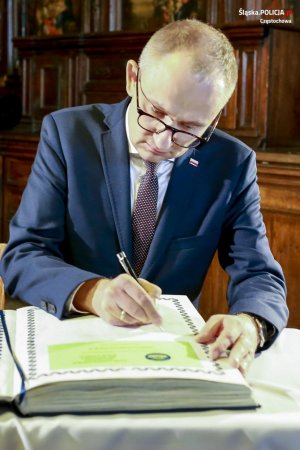 wiceminister spraw wewnętrznych i administracji z długopisem w ręku dokonuje wpisu do dużej księgi paiątkowej