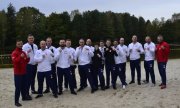 Reprezentacja Polskiej Policji na Mistrzostwach Polski Służb Mundurowych w kickboxingu - zawodnicy i zawodniczki w dresach na piasku pozują do zdjęcia