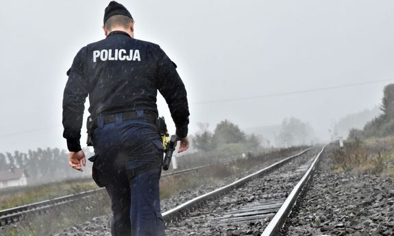 policjant w deszczu idzie po torach