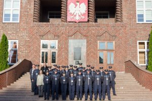 Wspólne zdjęcia na schodach głównego budynku dydaktycznego z herbem Polski w tle.