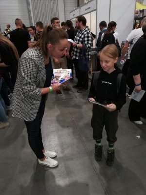 Przedstawicielka Biura Komunikacji Społecznej KGP wręcza komiks „Rabusie dyliżansów”.