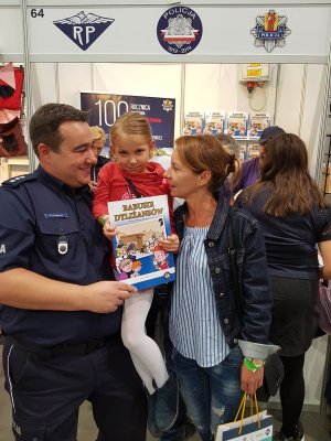 Przedstawiciel Biura Komunikacji Społecznej KGP z małą fanką komiksów.