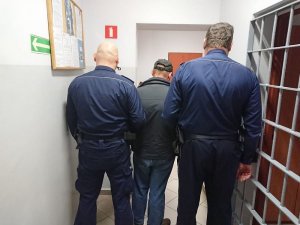 Mężczyzna który dokonał biestialskiego czynu na kocie w obstawie dwóch policjantów.