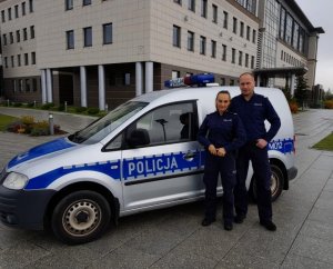 umundurowani policjanci stojący przed radiowozem