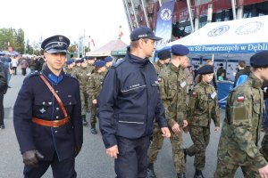 statysta w mundurze policji z lat 20 tych, policjant we współczesnym mundurze i uczniowie klasy mundurowej