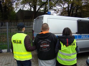 dwaj policjanci prowadzą zatrzymanego mężczyznę