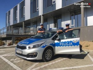 dwaj policjanci stoją przy radiowozie