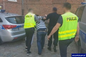 Policjanci prowadza zatrzymanego mężczyznę