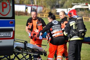 ratownicy medyczni i strażacy podczas transportu rannego do karetki pogotowia