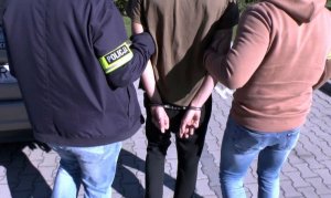 policjanci prowadzą zatrzymanego mężczyznę
