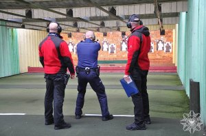 dwaj instruktorzy i policjant, który strzela w pozycji stojącej