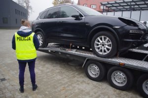 odzyskany samochód marki Porsche na lawecie obok stoi policjantka