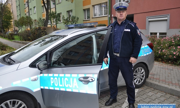 policjant stoi przy radiowozie