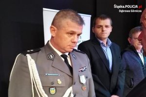 Podkom. Mariusz Śmiałkowski z Komendy Miejskiej Policji w Dąbrowie Górniczej  podczas uroczystości wręczenia odznaczenia w tle inni uczestnicy