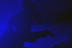 Policjant w ciemnym pomieszczeniu z bronią i w masce przeciwgazowej.