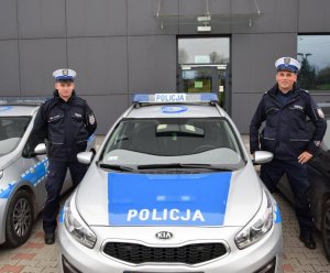 dwaj policjanci stoją przy radiowozie