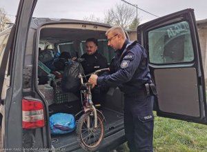 dwaj policjanci wyjmują z samochodu zebrane rzeczy