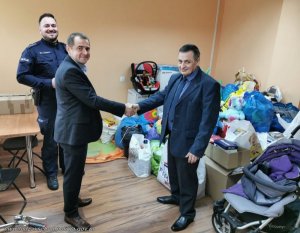 policjant oraz dwaj mężczyźni z zebranymi rzeczami