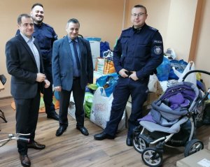 dwaj policjanci oraz dwaj mężczyźni z zebranymi rzeczami