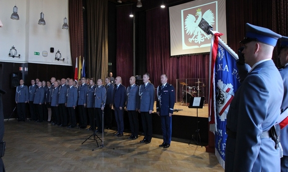 zgromadzeni goście stoją śpiewając hymn