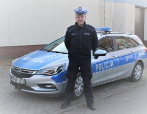 policjant stoi przy radiowozie