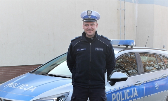 policjant stoi przy radiowozie