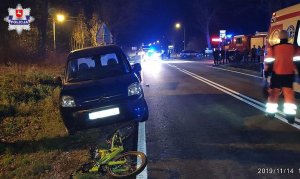 samochód stojący na poboczu i leżący przed nim dziecięcy rowerek