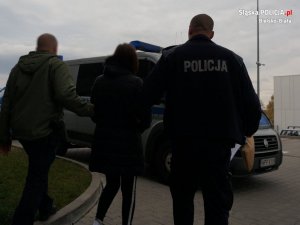 Policjanci prowadzą podejrzaną do radiowozu