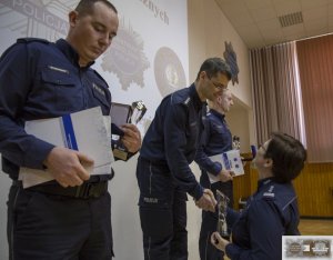 trzej najlepsi policjanci stoją na podium i odbierają nagrody oraz statuetki