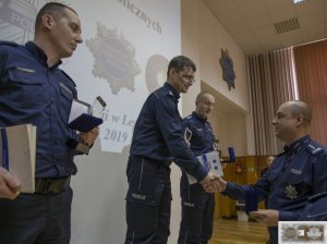 trzej najlepsi policjanci stoją na podium i odbierają nagrody oraz statuetki