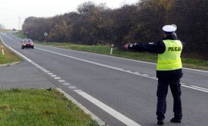 policjant zatrzymuje jadący samochód