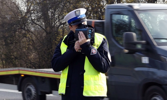 Policjant ruchu drogowego prowadzący pomiar prędkości pojazdów