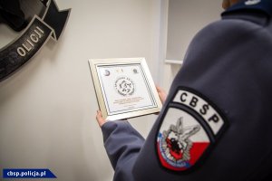 policjant trzyma w ręku oprawiony w ramę dyplom