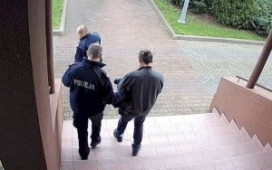 policjant prowadzi zatrzymanego mężczyznę