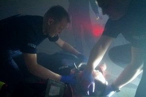 Zaopatrywanie ran policjanta w zadymionym i zaciemnionym pomieszczeniu.
