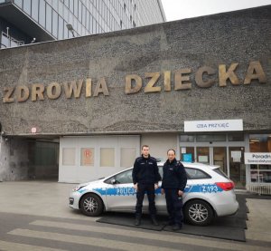 dwaj policjanci stoją przy radiowozie